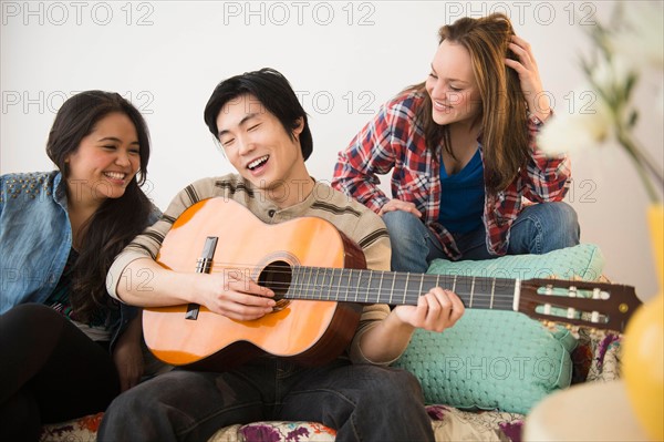 Young women listening to man playing guitar