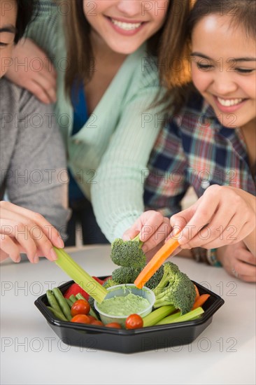Young women and man eating fresh veggies