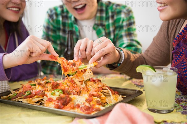 Young women and man eating nachos with melted cheese