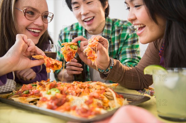 Young women and man eating nachos with melted cheese