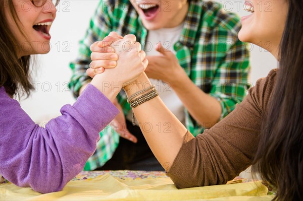 Young women and man arm wrestling