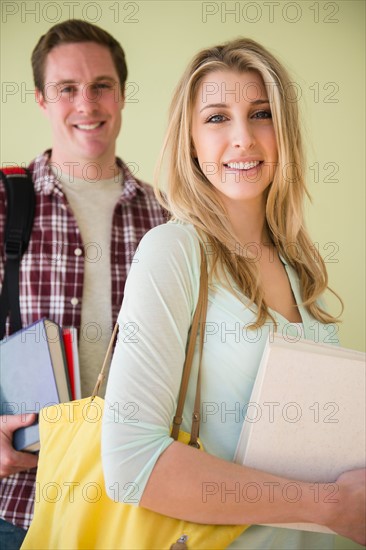 Studio shot of couple carrying books and files