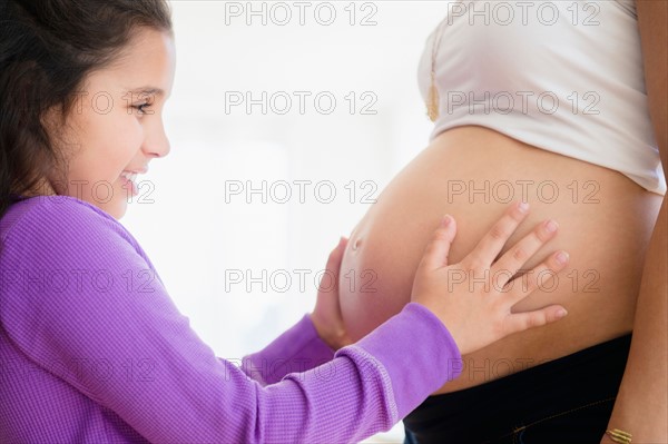 Girl (8-9) touching pregnant mother's belly