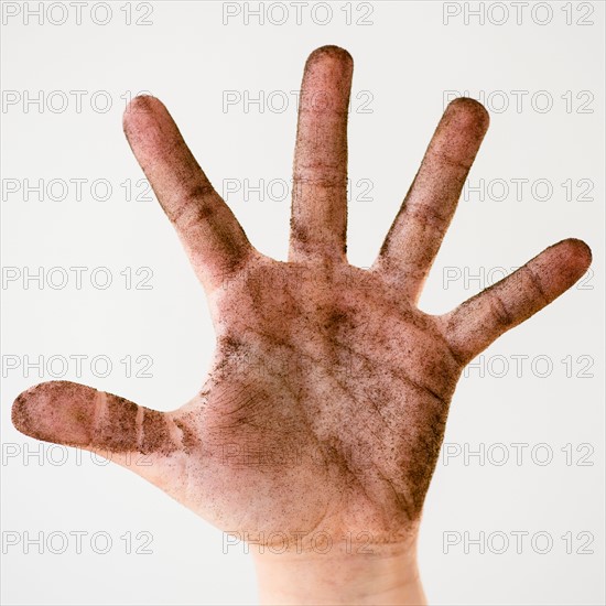 Child hand covered with plant soil