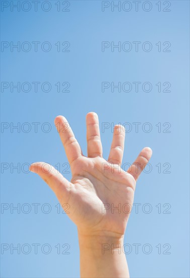 Girl's (8-9) palm against blue sky