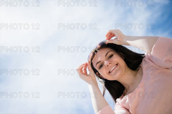 Portrait of young woman standing against cloudy sky