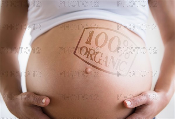 Mid section of pregnant woman with label on belly