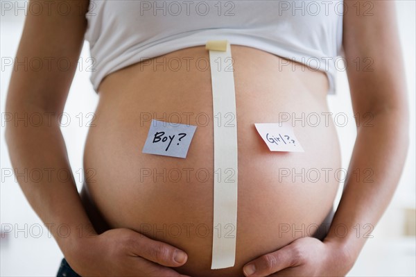 Mid section of pregnant woman with name tags on belly