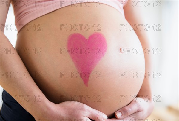 Mid section of pregnant woman with drawing of heart on belly