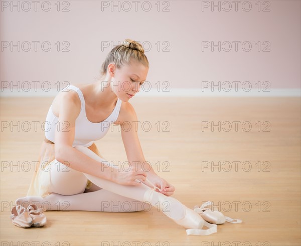 Portrait of teenage (16-17) ballet dancer tying her ballet shoe