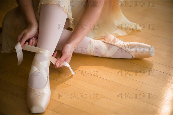 Close up of ballet dancer (16-17) tying her ballet shoe