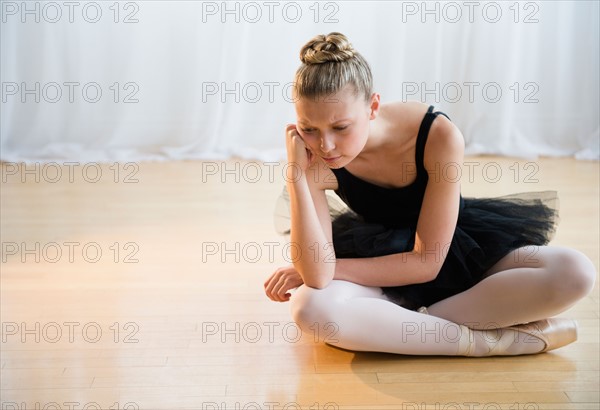 Portrait of tired teenage (16-17) ballet dancer sitting on floor