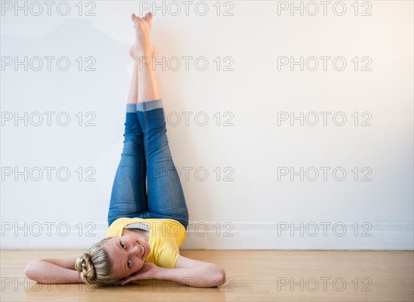 Portrait of teenage (16-17) ballerina lying down with feet up against wall