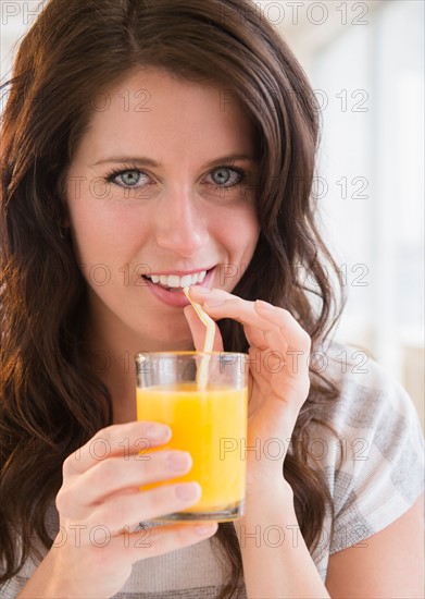 Portrait of young woman holding glass of orange juice