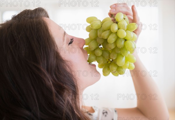 Portrait of young woman eating grapes