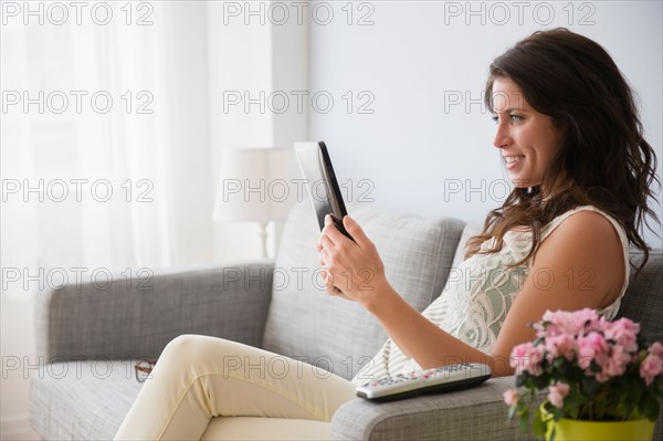 Young woman on sofa reading on digital tablet