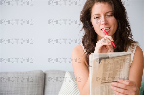 Young woman on sofa doing crossword puzzle