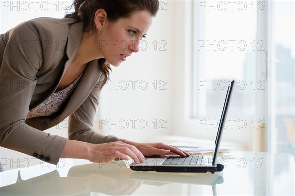 Busy woman in office using laptop