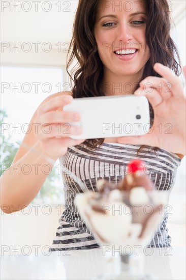 Portrait of woman photographing ice cream sundae