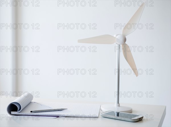 Studio Shot of small wind turbine, mobile phone and note pad on desk