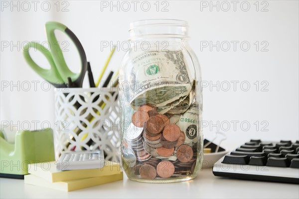 Studio Shot of jar full of money on desk