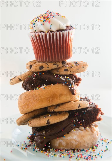 Studio Shot of tower made of cookies, brownie, donuts with cupcake on top