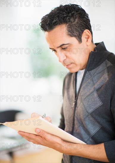 Portrait of man holding documents and writing