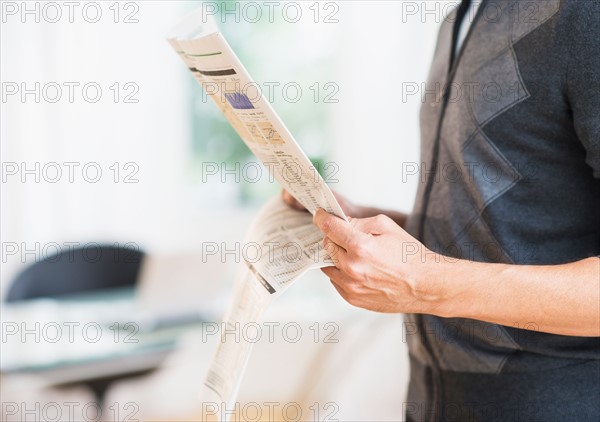 Mid section of man holding newspaper