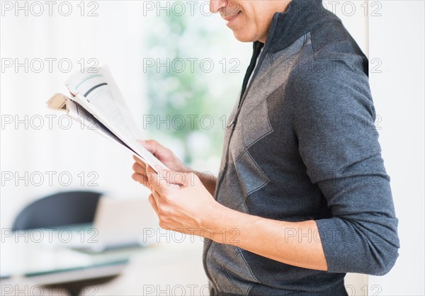 Mid section of man holding newspaper