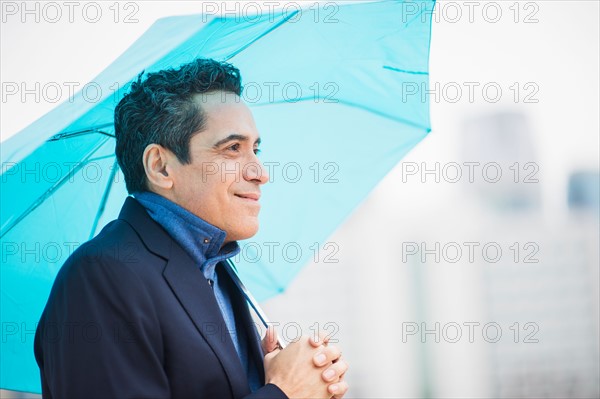 Portrait of man holding blue umbrella