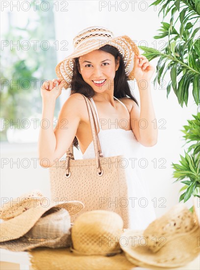 Portrait of mid adult women trying on straw hat