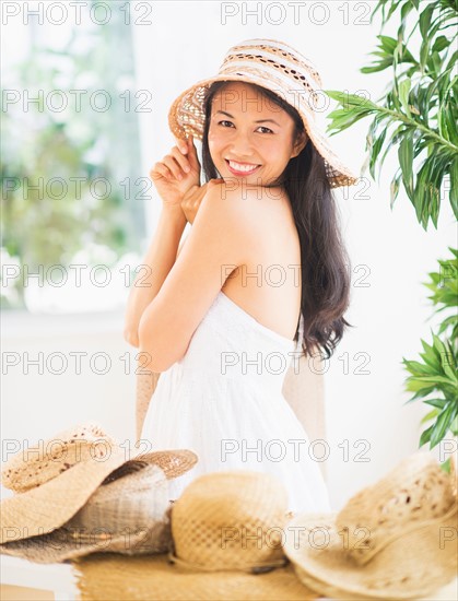 Portrait of mid adult women trying on straw hat