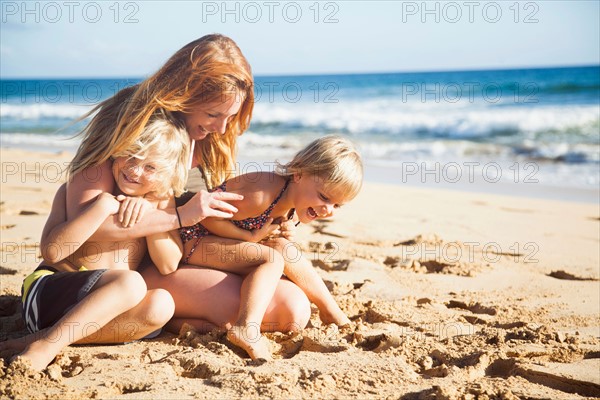 Mother with son (6-7) and daughter (2-3) on beach