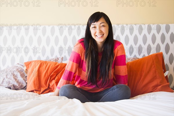 Portrait of mid adult woman sitting on bed