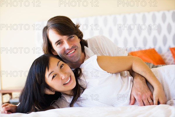 Pregnant wife with husband cuddling on bed