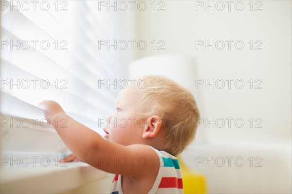 Baby boy (6-11 months) looking through window