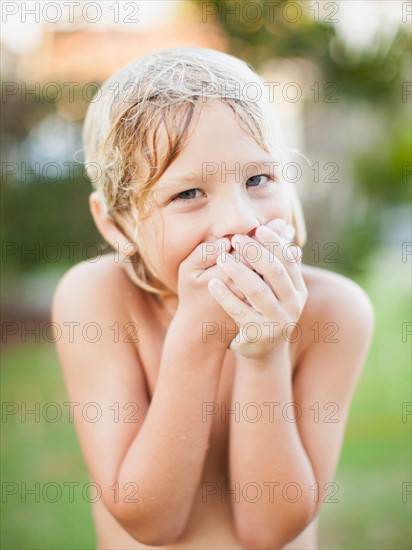 Portrait of boy (8-9) with hands covering mouth