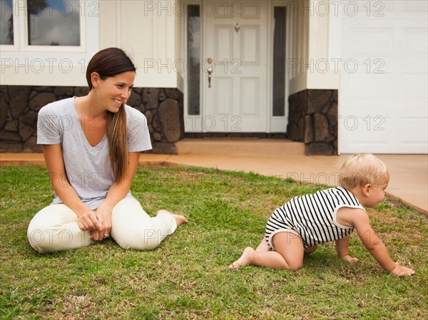 Mother with baby boy (6-11 months) in front of house