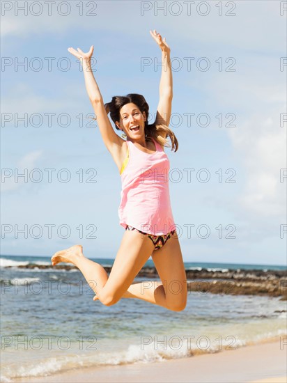 Young woman jumping on beach