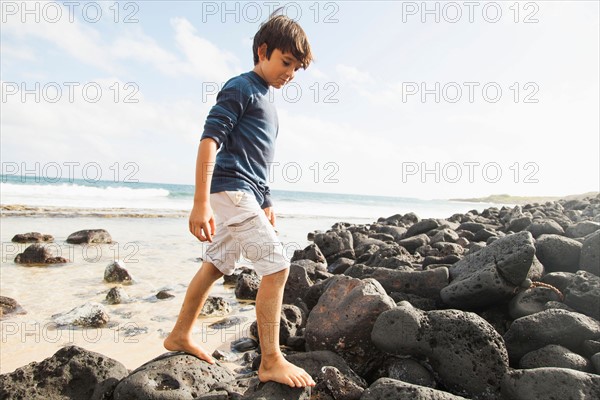 Boy (10-11) walking on stones on beach
