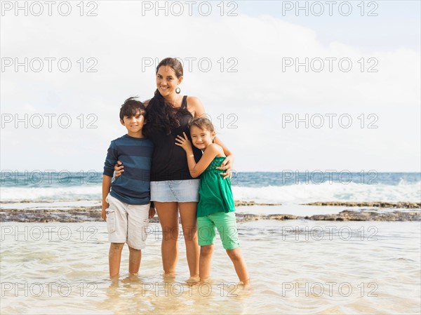 Portrait of girl (6-7) and boy (10-11) standing on beach with mother