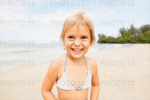 Smiling girl (2-3) on sandy beach