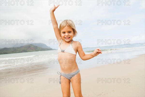 Smiling girl (2-3) on sandy beach