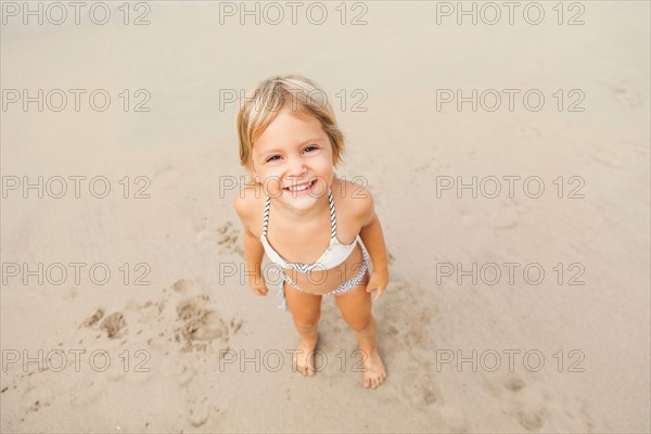 Smiling girl (2-3) on sandy beach