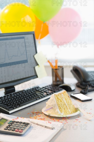 Studio shot of office workspace with cake and balloons.