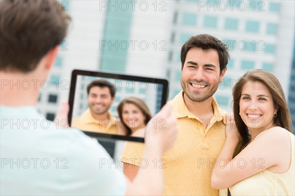 Man using tablet pc to take picture of friends.