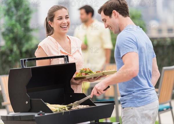 Friends enjoying barbecue in garden.