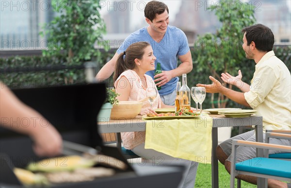 Friends enjoying barbecue in garden.