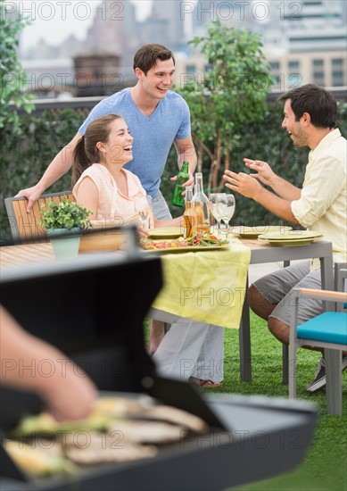 Friends enjoying barbecue in garden.