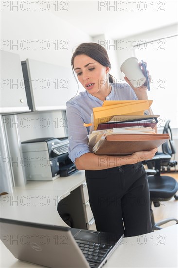 Business woman holding stack of documents and coffee cup.